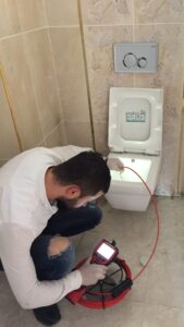 Banyo asma klozet giderine kırmızı kablolu endoskopik kamera salarak görüntülü sızıntı ve tıkanıklık analizi yapan Ergene tesisat hizmetleri ekibi